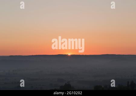 Blick auf den Sonnenaufgang über den Somerset-Ebenen vom Glastonbury Tor in Somerset im späten Frühling Stockfoto