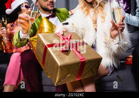 Interracial Freunde in hellen Kleidern feiern mit Gläsern Champagner auf grauem Hintergrund Stockfoto