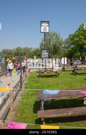 The Kings Head mit vielen Bänken und Fahnen, an denen Menschen an einem Sommertag in der Nähe des Wasserrands von Wroxham vorbeilaufen Stockfoto