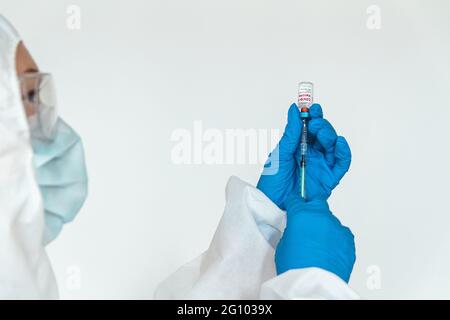 Arzt oder Krankenschwester in einem Schutzanzug hält eine Spritze und covid 1 Stockfoto