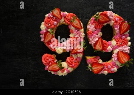 Schöner Kuchen in Form der Nummer 99. Modernes, trendiges Design. Frühlingshafte Dekoration. Speicherplatz kopieren. Low-Taste. Ungewöhnlich helles Dessert. Geburtstagskarte. Stockfoto