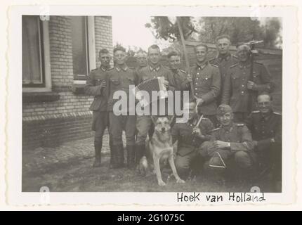 Deutsche Soldaten machen Musik. Eine Gruppe Wehrmachtsoldaten in Hoek van Holland musizieren. Ein Akkordeon, ein Dreieck, Zimbeln und einen Hund zu sehen. Stockfoto