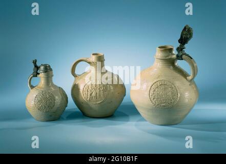 Weinkrug mit festem Deckel vom v.O.C.-Schiff, dem 'weißen Löwen'. Weinkrug mit festem Deckel von V.O.C. Schiff der 'weiße Löwe', 100% präsent. Weinglas mit balusterförmiger Wand in schmalen Hals und kleinem Mund fertig. Auf halbem Weg durch den Hals eine Kante aus Lehm. Aus dieser Höhe läuft ein vertikales Ohr zur Schulter. Auf dem Ohr befindet sich die Befestigung eines Blechventildeckels. Auf der Schulter verläuft die Schnittlinie um die Kanne. Am Bauch: Drei Reliefmedaillons mit Wappen. Grau-weiße Glasur auf crème-Scherbe. Hals mit radialen Rippen verziert. Stockfoto