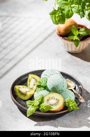 Hausgemachte Kiwi-Popsicles, mit Minzblättern auf einem betonierten Hintergrund. Selektiver Fokus, Kopierbereich Stockfoto