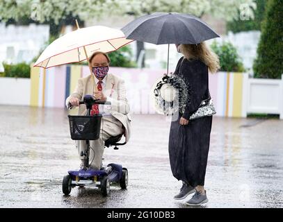 Rennfahrer schützen sich unter Regenschirmen während des Cazoo Derby Festivals auf der Epsom Racecourse am ersten Tag vor dem Regen. Bilddatum: Freitag, 4. Juni 2021. Stockfoto