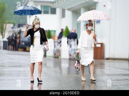 Rennfahrer schützen sich unter Regenschirmen während des Cazoo Derby Festivals auf der Epsom Racecourse am ersten Tag vor dem Regen. Bilddatum: Freitag, 4. Juni 2021. Stockfoto