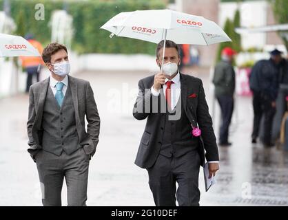 Rennfahrer schützen sich unter Regenschirmen während des Cazoo Derby Festivals auf der Epsom Racecourse am ersten Tag vor dem Regen. Bilddatum: Freitag, 4. Juni 2021. Stockfoto