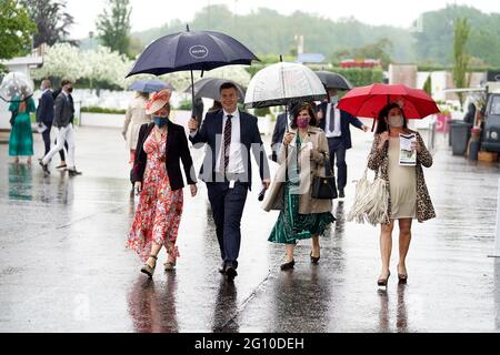Rennfahrer schützen sich unter Regenschirmen während des Cazoo Derby Festivals auf der Epsom Racecourse am ersten Tag vor dem Regen. Bilddatum: Freitag, 4. Juni 2021. Stockfoto