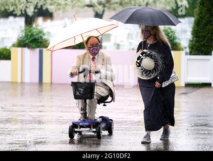 Rennfahrer schützen sich unter Regenschirmen während des Cazoo Derby Festivals auf der Epsom Racecourse am ersten Tag vor dem Regen. Bilddatum: Freitag, 4. Juni 2021. Stockfoto