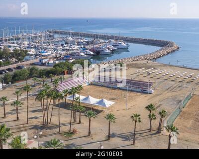 Top Luftbild mit Blick auf Finikoudes Palmenpromenade, Mittelmeer, Yachten im Hafen und Beach-Volleyball-Platz an einem sonnigen Tag. Stockfoto