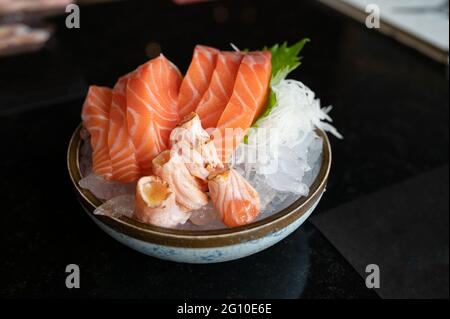 Roher Sashimi-Lachs in Scheiben geschnitten und geräucherter Lachs auf Eis in einer Schüssel im japanischen Restaurant Stockfoto