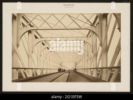 Eisenbahnbrücke über die Lek bei Kuilenburg (Culemborg). Schönscheidt hatte die neue Rheinbrücke in Köln bereits fotografiert, als er gebeten wurde, die Eisenbahnbrücke über die Lek in Kuilenburg zu fotografieren. Sie war damals mit 150 Metern die längste Eisenbahnbrücke Europas. Es war gerade erst 1868 fertiggestellt worden, als dieses Foto aufgenommen wurde. Der Zuschnitt, der die perspektivische Wirkung der Stahlträger erhöht, ist überraschend modern. Stockfoto