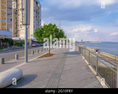 Lange leere Piale Pasha Betonpromenade entlang des blauen Mittelmeers in Larnaca Stadt, Zypern. Ruhige Meeresstadtlandschaft mit bewölktem Himmel über dem Wasser Stockfoto