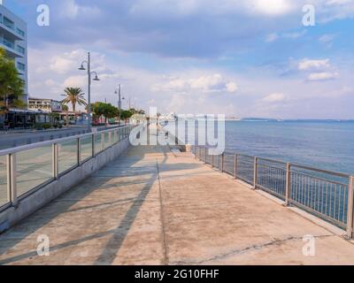 Lange leere Piale Pasha Betonpromenade entlang des blauen Mittelmeers in Larnaca Stadt, Zypern. Ruhige, maritime, herbstliche Stadtlandschaft mit bewölktem Himmel. Stockfoto