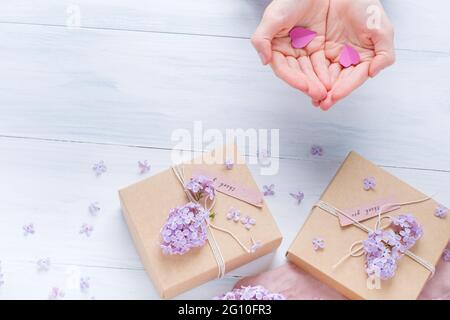 Weibliche Hände, die Papierherzen halten. Flach liegend, Hände und Geschenk-Box, Draufsicht. . Hochwertige Fotos Stockfoto