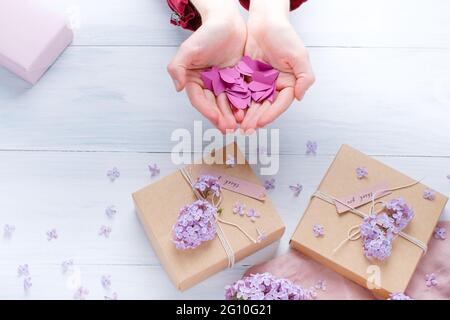 Weibliche Hände, die Papierherzen halten. Flach liegend, Hände und Geschenk-Box, Draufsicht. . Hochwertige Fotos Stockfoto