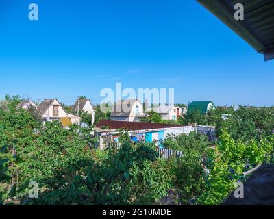 Blick von oben auf die zweistöckigen Landhäuser mit kleinen Flächen und grünen Gärten. Konzept des sowjetischen Erbes. Stockfoto