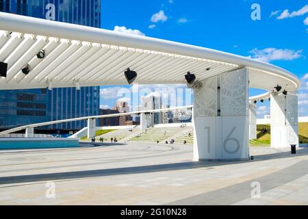 Modernes Erholungsgebiet mit abstrakten architektonischen Formen. Touristen ruhen vor dem Hintergrund von Wolkenkratzern. Stockfoto