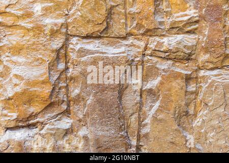 Steinhintergrundwand aus gelbem krimkalk, mit transparentem Lack überzogen. Stockfoto