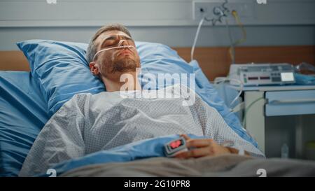 Krankenstation: Porträt eines hübschen jungen Mannes, der die Nasal-Kanüle trägt und im Bett schläft, der sich nach Krankheit vollständig erholt. Männlicher Patient, Der Von Seinem Träumen Kann Stockfoto