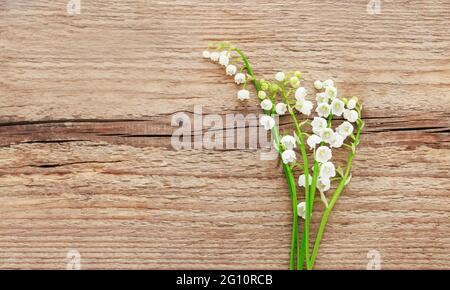 Maiglöckchen Blumen auf braunem Holzhintergrund, Kopierraum. Stockfoto