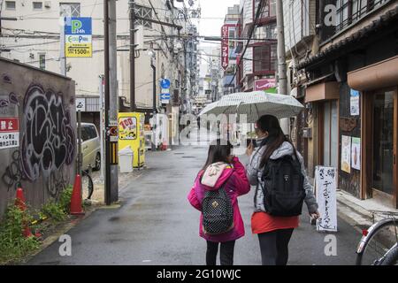 OSAKA, JAPAN - 24. Dez 2019: Osaka, Japan - 28. Nov 2019: Menschen mit Sonnenschirmen auf der nassen Straße am Regentag in Osaka, Japan. Stockfoto