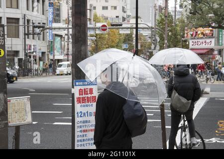 OSAKA, JAPAN - 24. Dez 2019: Osaka, Japan - 28. Nov 2019: Menschen mit Sonnenschirmen auf der nassen Straße am Regentag in Osaka, Japan. Stockfoto