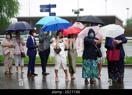Rennfahrer schützen sich unter Regenschirmen während des Cazoo Derby Festivals auf der Epsom Racecourse am ersten Tag vor dem Regen. Bilddatum: Freitag, 4. Juni 2021. Stockfoto