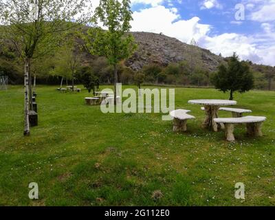Schöner natürlicher Picknickbereich im Freien mit Stein- und Holztischen Stockfoto