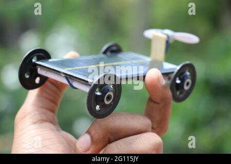 Hand halten Solar Air Auto. Auto, das auf Solarenergie arbeitet, in der Hand gehalten auf Naturhintergrund, das ein umweltfreundliches Konzept zeigt Stockfoto