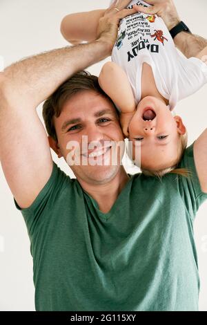 Lächelnder Vater hält das kleine lachende Mädchen auf den Kopf. Nahaufnahme. Hochformat Stockfoto