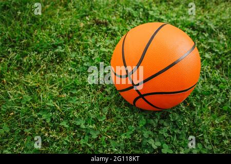 Basketball-Ball auf einem frischen grünen Gras. Kinderspielplatz im Freien. Stockfoto