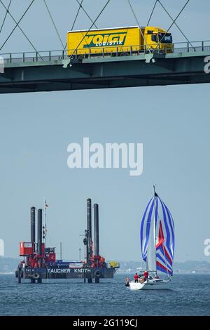 Fehmarn, Deutschland. Juni 2021. Ein LKW fährt über die Fehmarsund-Brücke, während unten während der Probebohrungen im Fehmarsund ein Bohrgerät zu sehen ist. Die Bohrungen dienen der Planung des Baus des Fehmarsundtunnels zwischen dem Schleswig-holsteinischen Festland und der Insel Fehmarn. Quelle: Gregor Fischer/dpa/Alamy Live News Stockfoto