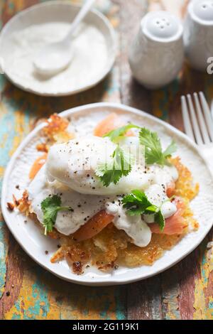 Rosti Eggs royale. Kartoffelpfannkuchen mit geräuchertem Lachs, Sauce Hollandaise, pochiertem Ei und Koriander Stockfoto