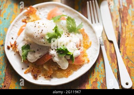 Rosti Eggs royale. Kartoffelpfannkuchen mit geräuchertem Lachs, Sauce Hollandaise, pochiertem Ei und Koriander Stockfoto