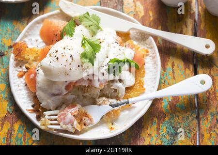 Rosti Eggs royale. Kartoffelpfannkuchen mit geräuchertem Lachs, Sauce Hollandaise, pochiertem Ei und Koriander Stockfoto