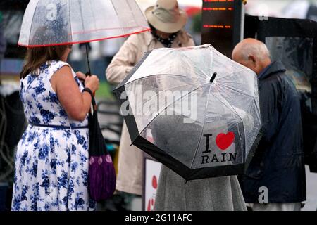 Rennfahrer schützen sich vor dem Regen unter Regenschirmen, während sie am ersten Tag des Cazoo Derby Festivals auf der Epsom Racecourse eine Wette platzieren. Bilddatum: Freitag, 4. Juni 2021. Stockfoto