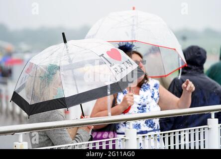 Rennfahrer schützen sich unter Regenschirmen während des Cazoo Derby Festivals auf der Epsom Racecourse am ersten Tag vor dem Regen. Bilddatum: Freitag, 4. Juni 2021. Stockfoto