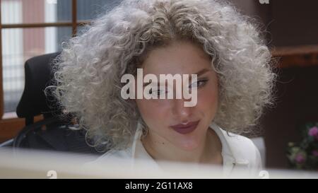 Lockiges weißes Haar Frau, die zu Hause am Computer arbeitet. Stockfoto