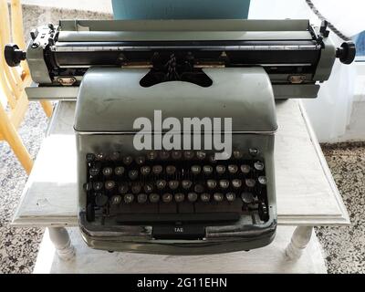 Antik graue Schreibmaschine mit kyrillischen Buchstaben und einem fehlenden Schlüssel steht auf weißem Holztisch Stockfoto