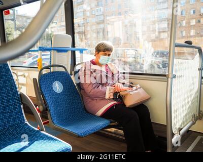 Moskau. Russland. 3. Juni 2021. Eine ältere grauhaarige Frau in einer Schutzmaske schläft während einer Fahrt in einem Stadtbus. Maßnahmen zum Schutz vor Viren Stockfoto