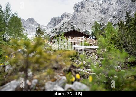 Mittenwald, Deutschland. Juni 2021. Hinter der Mittenwalder Hütte ist das Karwendelmassiv zu sehen. Die Schutzhütte nordwestlich unterhalb der westlichen Karwendelspitze auf 1518 Metern Seehöhe ist eine Alpenvereinshütte der Sektion Mittenwald des Deutschen Alpenvereins (DAV). (To dpa-Korr 'Strenge Corona-Regeln: Alpenverein fürchtet schwierige Hüttensaison' von 04.06.2021) Quelle: Matthias Balk/dpa/Alamy Live News Stockfoto