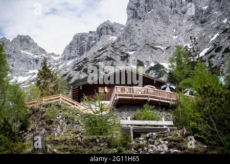 Mittenwald, Deutschland. Juni 2021. Hinter der Mittenwalder Hütte ist das Karwendelmassiv zu sehen. Die Schutzhütte nordwestlich unterhalb der westlichen Karwendelspitze auf 1518 Metern Seehöhe ist eine Alpenvereinshütte der Sektion Mittenwald des Deutschen Alpenvereins (DAV). (To dpa-Korr 'Strenge Corona-Regeln: Alpenverein fürchtet schwierige Hüttensaison' von 04.06.2021) Quelle: Matthias Balk/dpa/Alamy Live News Stockfoto