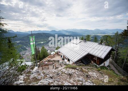 Mittenwald, Deutschland. Juni 2021. Die Stadt Mittenwald und die bayerischen Alpen sind hinter der Mittenwalder Hütte zu sehen. Die Schutzhütte nordwestlich unterhalb der westlichen Karwendelspitze auf 1518 Metern Seehöhe ist eine Alpenvereinshütte der Sektion Mittenwald des Deutschen Alpenvereins (DAV). (To dpa-Korr 'Strenge Corona-Regeln: Alpenverein fürchtet schwierige Hüttensaison' von 04.06.2021) Quelle: Matthias Balk/dpa/Alamy Live News Stockfoto