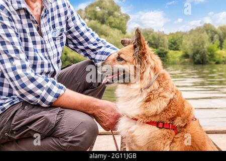 Man and his dog sitting on wooden pier. Holiday with an animal concept. Summer time Stockfoto