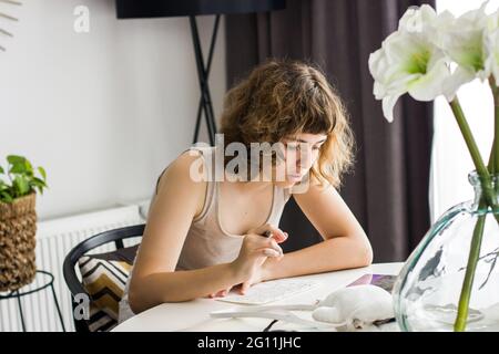 Junges Mädchen macht Hausaufgaben am weißen Tisch. Home Bildung und Homeschooling Stockfoto