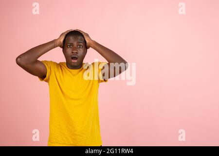 Warum ist das so? Schönes afro männliches halblanges Porträt isoliert auf trendigem Studiohintergrund. Der junge, emotional überraschte, frustrierte und verwirrte Mann. Stockfoto