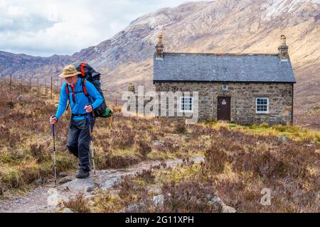 Ein Rucksacktourist außerhalb eines bothy in den North West Highlands von Schottland Stockfoto