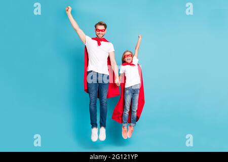 Ganzkörper-Porträt von tapferen kleinen Schüler positive Kerl fliegen heben Arme Fäuste bis isoliert auf blauem Hintergrund Stockfoto