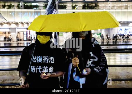 Tokio, Japan. Juni 2021. Während der Demonstration halten Demonstranten, die Masken tragen, Kerzen und einen Regenschirm in der Hand. Prodemokratische Gruppen protestierten vor dem Bahnhof Shinjuku in Japan, um den 32. Jahrestag des Massakers auf dem Platz des Himmlischen Friedens zu begehen. Kredit: SOPA Images Limited/Alamy Live Nachrichten Stockfoto